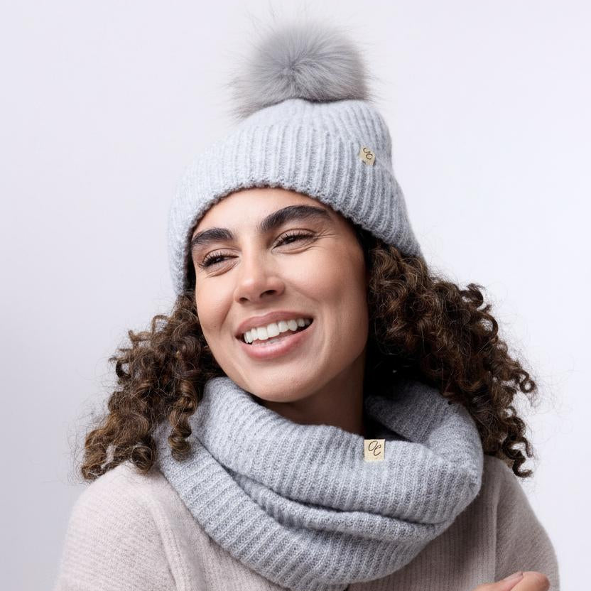 Woman wearing a gray knit hat and scarf on a white background